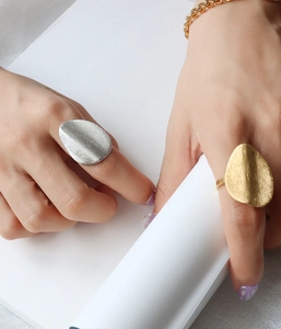 Macro view of irregular brushed gold ring and chain bracelet with matte texture