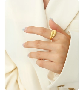 Close-up of a minimalist 18K gold plated chunky ring on a finger with a chic beige blazer