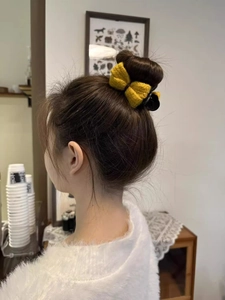 Detail of yellow knitted bow hair claw clip styled on a bun for autumn winter hairstyles