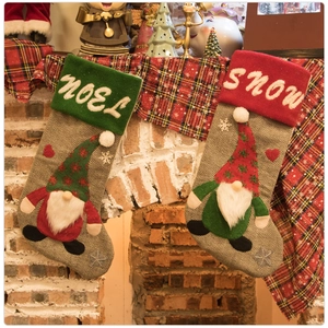 Detail of knitted Christmas stockings with faceless gnomes hanging by a cozy fireplace