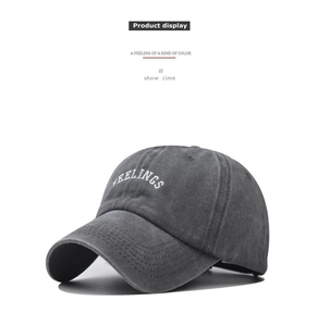 Detailed view of white FEELINGS embroidery on washed dark grey cotton baseball cap