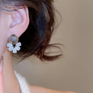 Detailed close-up of a flower-shaped ear stud featuring a taupe stone and zircon petals