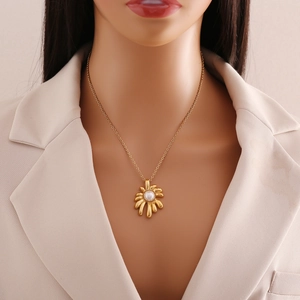 Golden flower necklace with pearl pendant worn over a beige suit on a mannequin