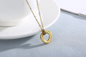 Close-up of golden irregular openwork pendant necklace on a textured gray background