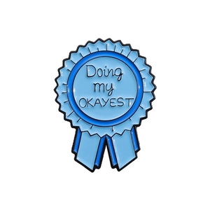 Light blue enamel medal brooch with Doing my OKAYEST slogan in geometric style