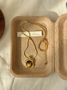 Detail of 18K gold plated tiger eye pendant necklace on vintage paper pulp tray