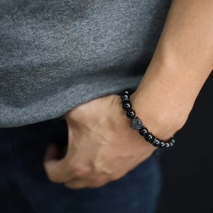 Close-up of men's black beaded leopard bracelet with green stone eyes on wrist