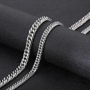 Macro shot of silver titanium steel Cuban link chain with polished finish on black pedestal