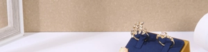 Detailed view of three gold leaf and pearl rings on a dark blue velvet display stand
