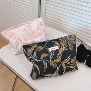 Detailsicht der floralen Jacquard-Stickerei und des simple wish-Etiketts auf Kosmetiktaschen