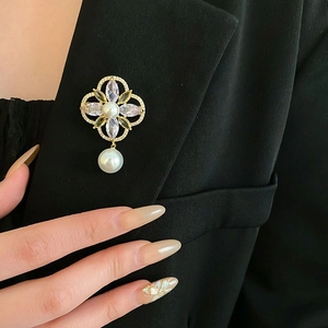 Detailed close-up of a flower pearl brooch with colorful gemstones on a black suit lapel