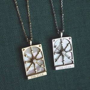 Vintage gold and silver tarot star necklaces with mother of pearl on green texture