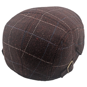 Detail of British style dark brown flat cap with herringbone texture and metal buckle