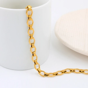 Detailed close-up of gold hexagonal chain links with Greek Meander pattern on a white cup