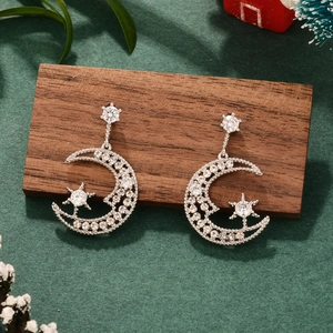 Star and moon earrings in silver with clear zircons on a festive green background