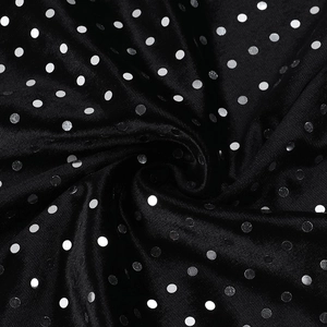 Close-up of sparkling silver polka dots on black velvet fabric with elegant draped folds