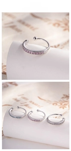 Dettaglio di ear cuff minimalisti in argento con gemme rosa, blu e bianche