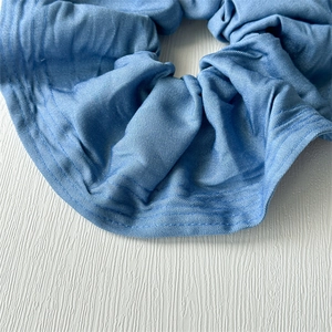 Detailed close-up showing the soft denim fabric texture and ruffles of the blue scrunchie