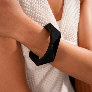 Close-up of a minimalist black resin geometric bangle worn on a model's wrist