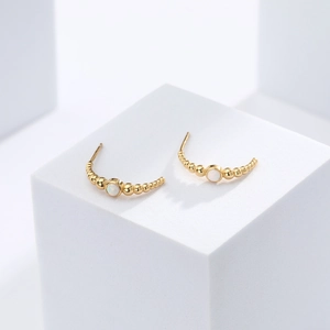 Detailed close-up of gold beaded stud earring featuring elegant white opal stones