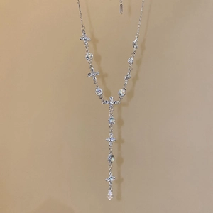 Detail of silver Y-shaped necklace featuring crystal crosses and waterdrop pendant