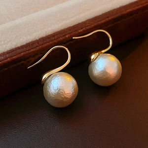 Vue macro d'élégantes boucles d'oreilles crochet dorées avec perles rondes