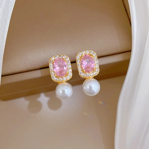 Detail of gold earrings featuring pink gemstones, crystal halo, and white pearls
