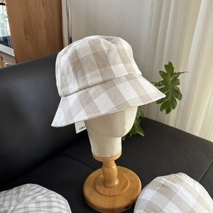 Close-up of beige gingham linen sun hat with breathable texture on display stand