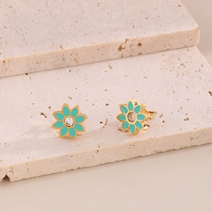 Détail de boucles d'oreilles marguerites dorées en émail vert avec un zircon étincelant