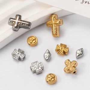 Detailed macro view of gold and silver cross-shaped stainless steel spacer beads for DIY jewelry