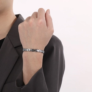 Macro view of men's bicolor stainless steel chain bracelet with nautical anchor detail