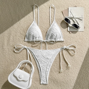 Flat lay of white textured bikini set with adjustable halter neck and side tie bottoms