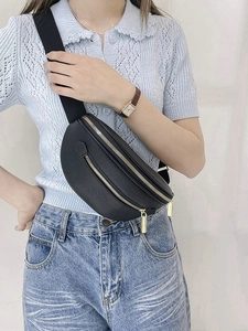 Sac banane chic en cuir grainé noir avec fermetures dorées porté en bandoulière