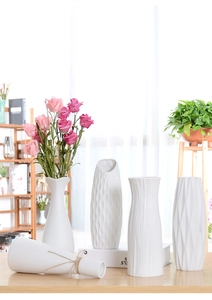 Close-up of white minimalist ceramic vases with twine detail and silk roses decoration