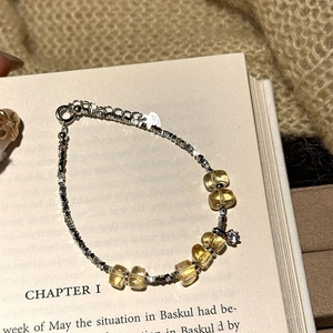 Elegant citrine and zircon beaded silver bracelet displayed on a vintage book page