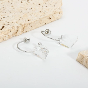 Detail view of silver stainless steel C-hoop earrings with clear crystal glass pendants