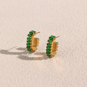 Macro detail of 18K gold plated hoop earrings featuring rectangular green zircon stones