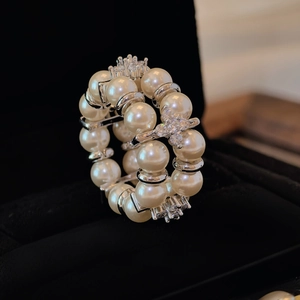 Macro shot of double-layered pearl ring with zircon flowers on black velvet box