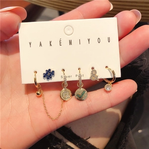 Detail of five-piece gold earring set with colorful cubic zirconia on a silver post card