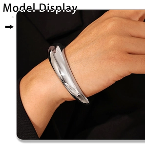 Close-up of a silver-toned chunky C-shape bangle with a smooth polished finish on a model
