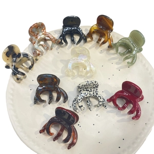 Set of ten acetate hair claws in leopard and solid colors on a white ceramic tray