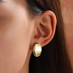 Close-up of elegant dome gold stud earrings on model with high polished metal surface