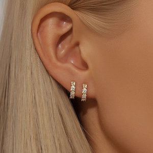 Close-up of golden double-row crystal huggie earrings worn on earlobe for detail