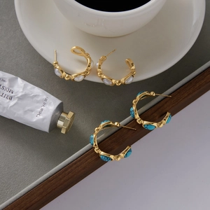 Close-up of gold stainless steel hoop earrings with blue turquoise and white pearls