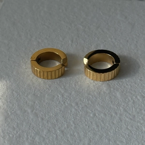 Close-up of golden round hoop earrings featuring vertical textured stripes and polished finish