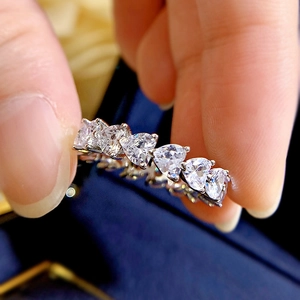 Detailed macro view of S925 silver heart-shaped diamond band held by fingers
