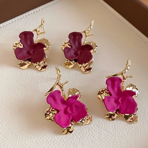 Detail of matte floral earrings in dark red and purple with hammered gold metal