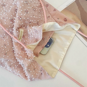 Detail of pink floral bag interior with mesh and pearls showing large capacity for phone