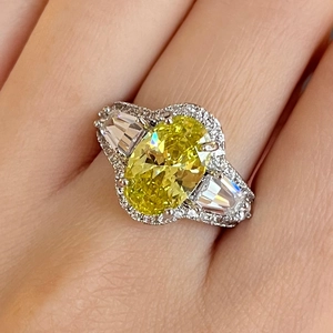 Macro-opname van een platina ring met ovale gele edelsteen en trapeziumvormige stenen