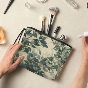 Leaf pattern makeup bag with zipper and handle, shown with beauty accessories on beige background